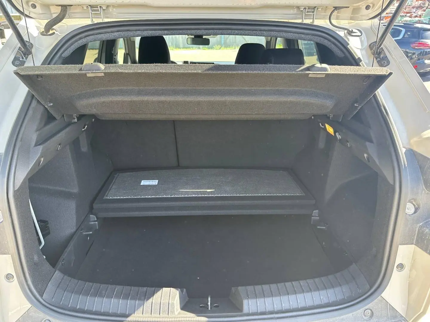 Coffre ouvert du Dacia Duster 2025 Sandstone, montrant la tablette cache-bagages et l’espace de rangement noir.