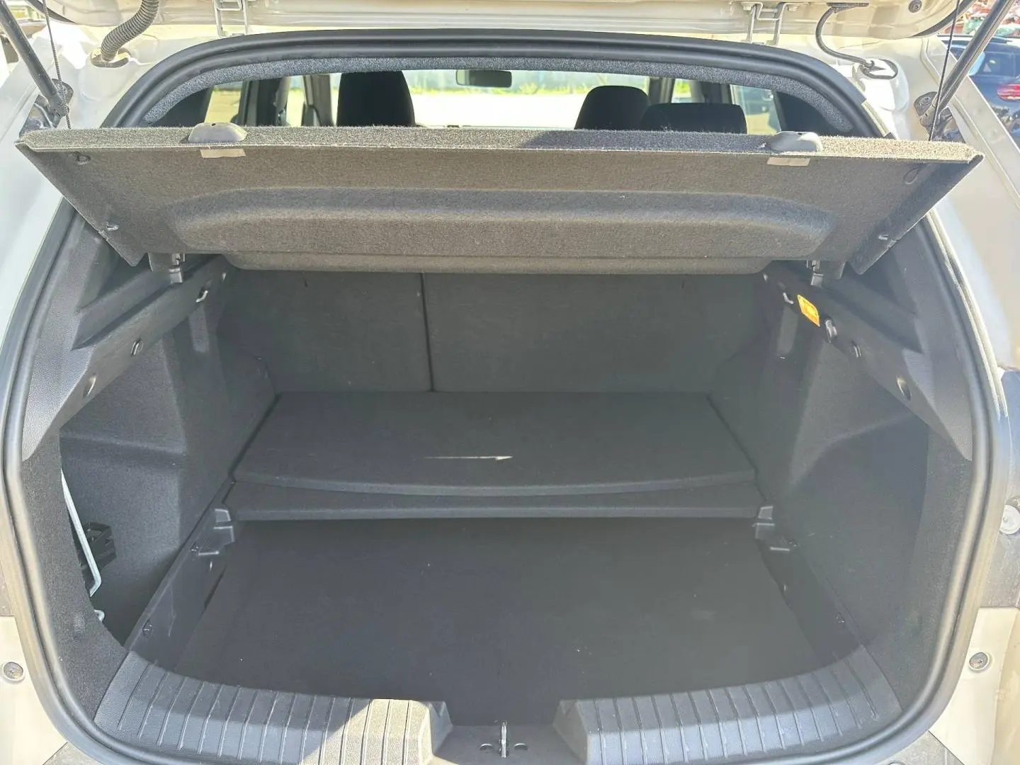 Coffre ouvert du Dacia Duster 2025 Sandstone, montrant le plancher de coffre mobile et l'espace de rangement intérieur.