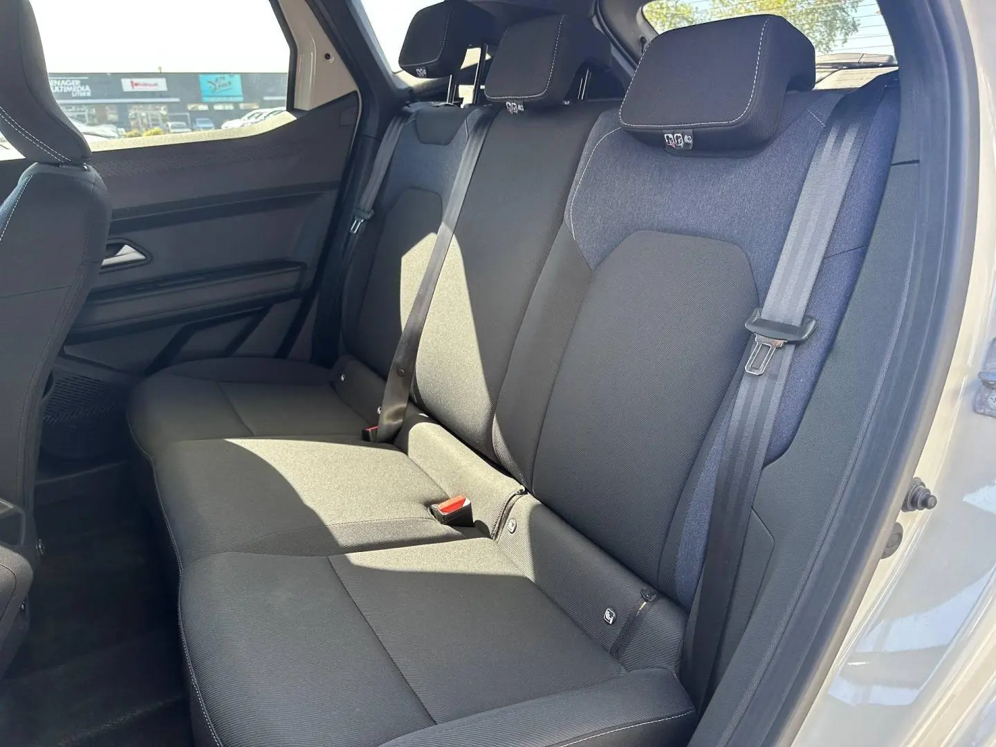 Vue latérale droite de la banquette arrière en tissu noir et bleu du Dacia Duster 2025, avec ceintures de sécurité visibles.