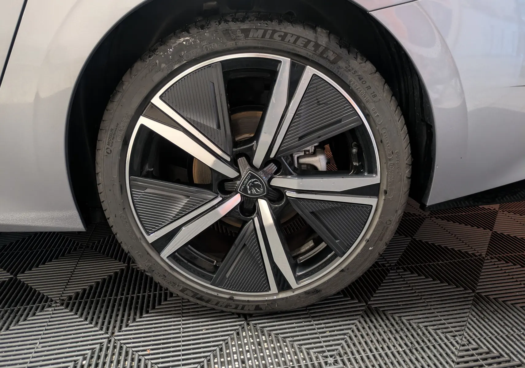 Vue arrière du coffre ouvert d'une Peugeot 308 SW Hybrid 145 gris, montrant l'espace de chargement vide et l'éclairage intérieur.