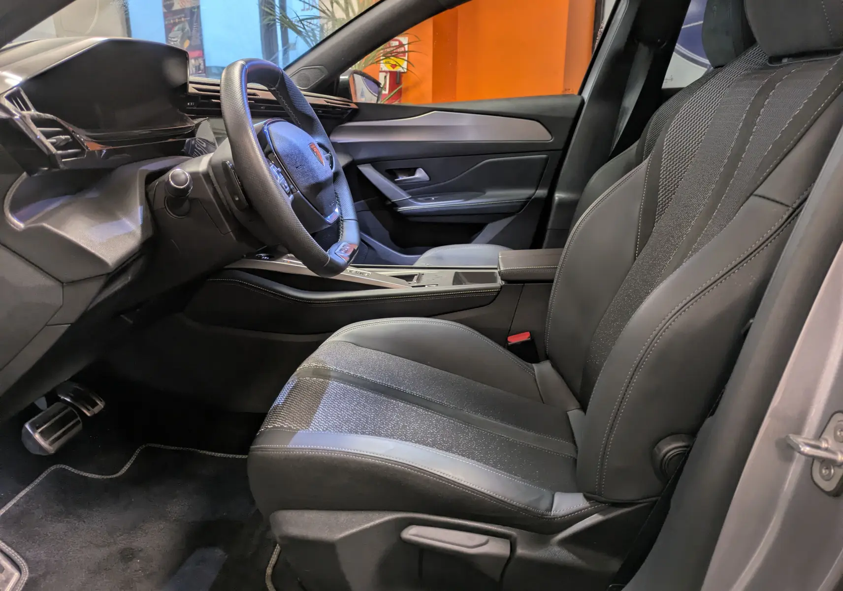 Gros plan sur la commande des vitres et rétroviseurs côté conducteur d’un Peugeot 308 SW gris, intérieur noir.