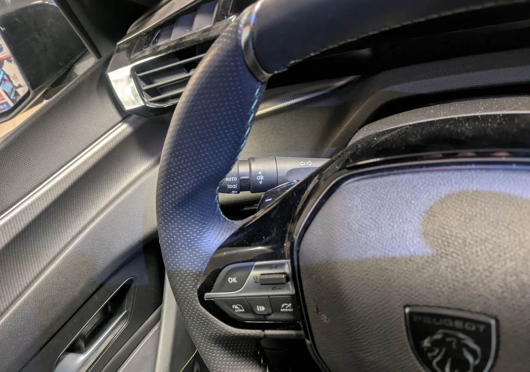 Intérieur côté conducteur de la Peugeot 308 SW Hybrid gris 2025, avec sellerie tri-matières et volant compact.