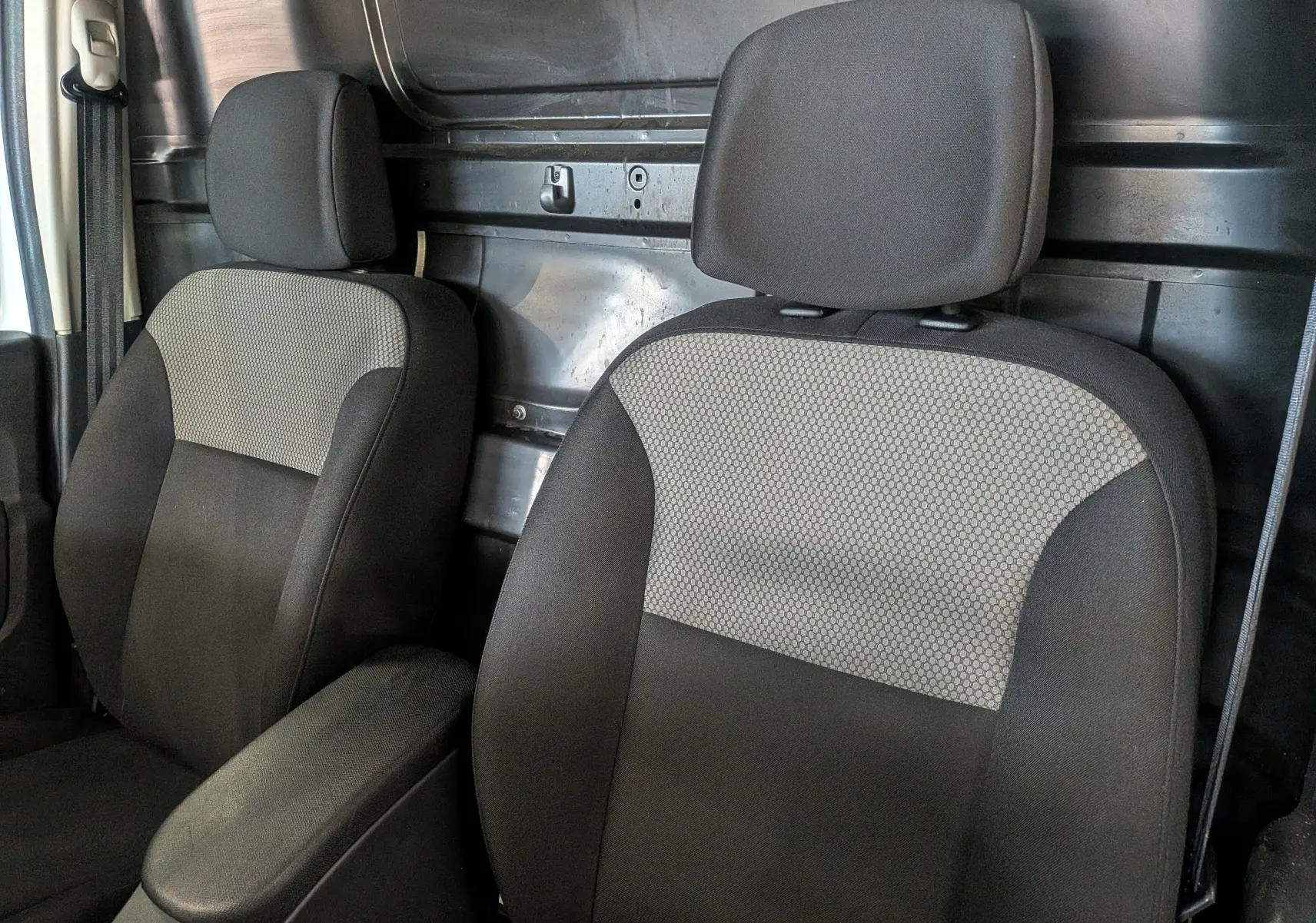 Gros plan sur les sièges avant en tissu noir et gris du Renault Kangoo Express Blanc Minéral, intérieur utilitaire visible.