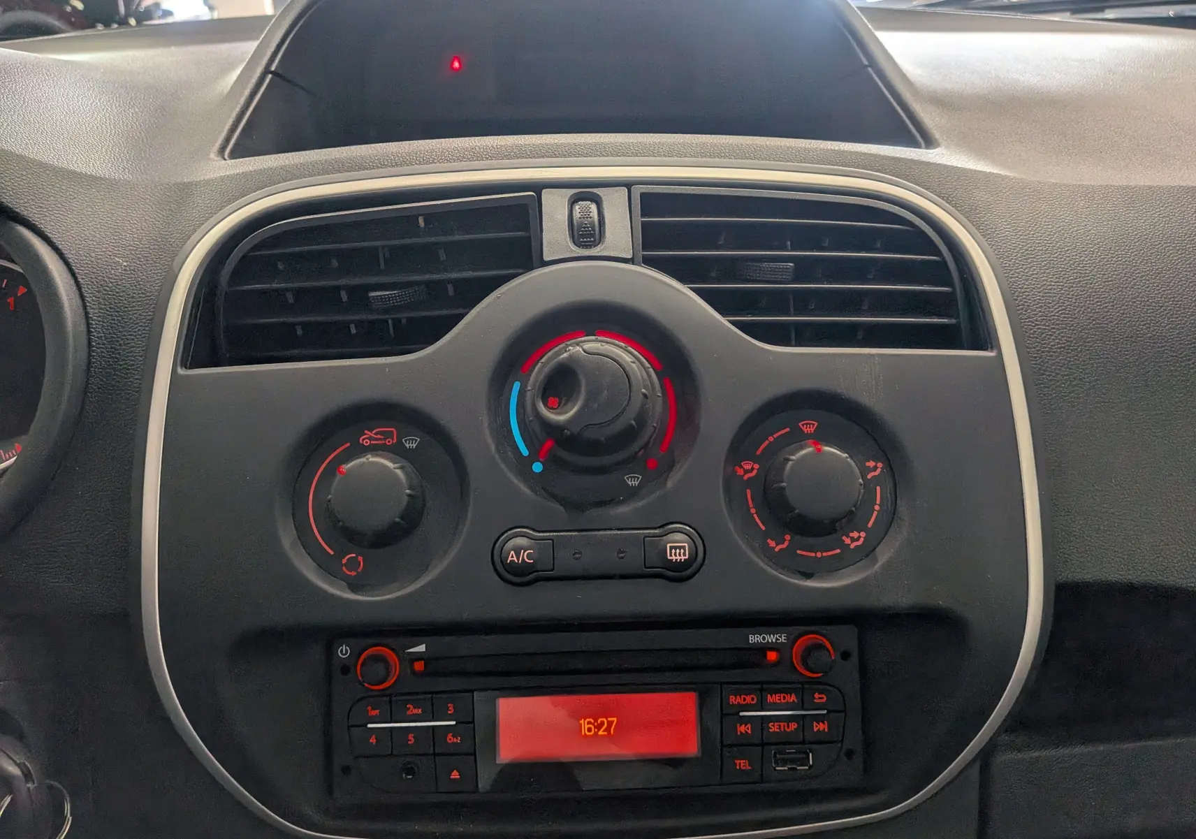Vue rapprochée du tableau de bord central du Renault Kangoo Express blanc, avec commandes de climatisation et radio intégrée.