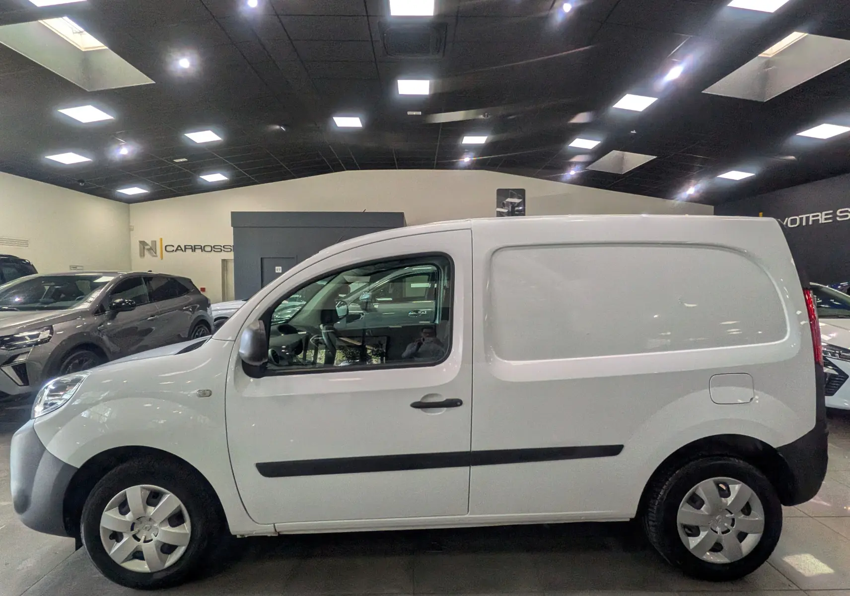Vue latérale droite du Renault Kangoo Express blanc minéral 2020 en version Blue dCi 95 CH Grand Confort dans un showroom.