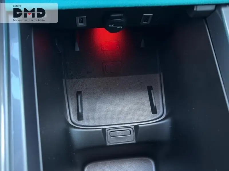 Gros plan sur le compartiment de recharge à induction avec prise 12V, éclairage rouge intérieur d'une FIAT 600 rouge.
