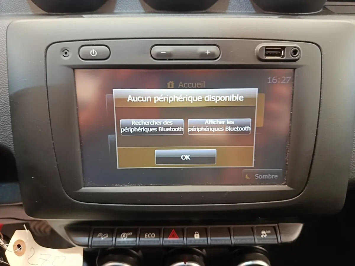 Vue rapprochée de l'écran tactile central du tableau de bord du Dacia Duster blanc, affichant un message Bluetooth.