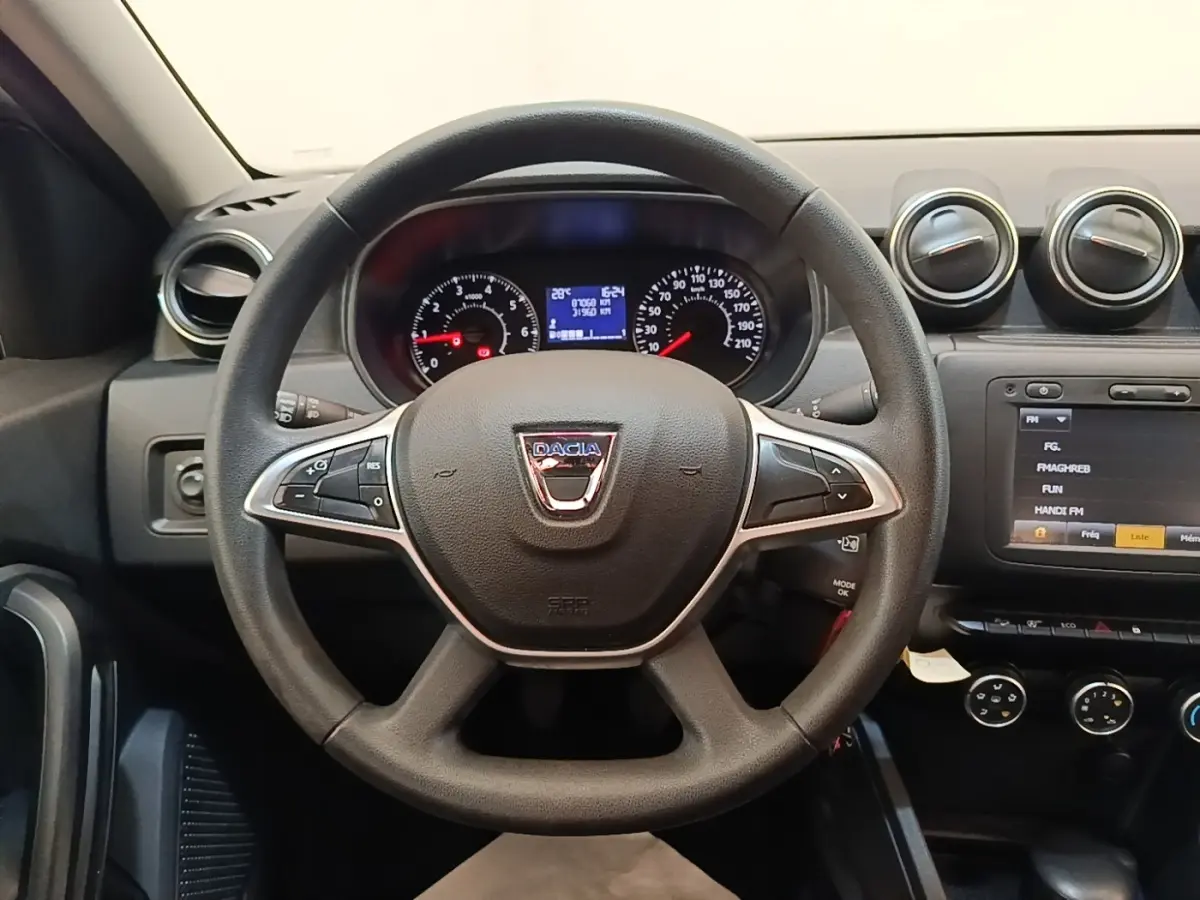 Vue intérieure centrée sur le volant cuir noir du Dacia Duster 2021 avec tableau de bord et écran tactile visible.