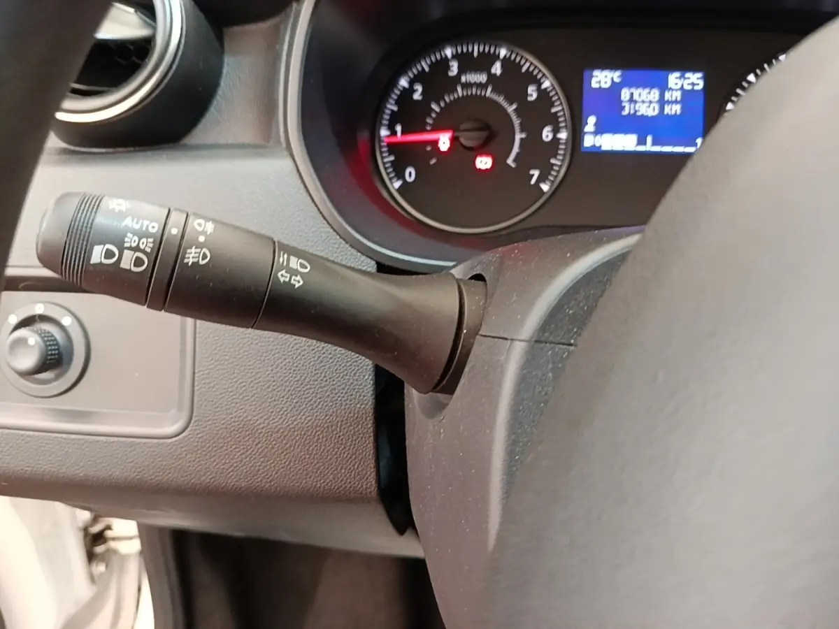 Gros plan sur le tableau de bord noir du Dacia Duster blanc, avec compte-tours et écran multifonctions bleu allumé.