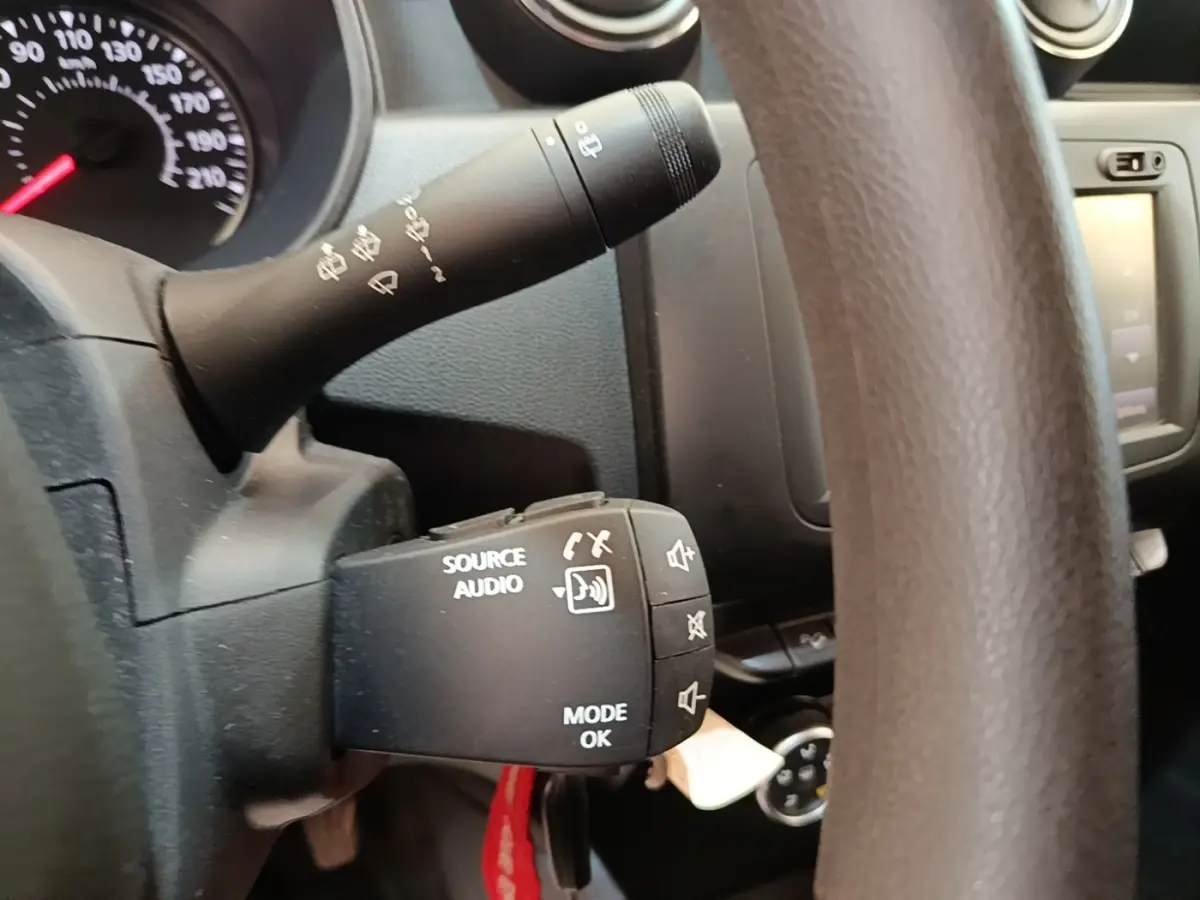 Gros plan sur le volant cuir synthétique du Dacia Duster blanc, avec commandes audio intégrées visibles.