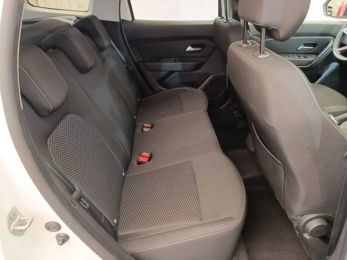 Vue intérieure arrière côté gauche du Dacia Duster blanc, montrant la banquette arrière en tissu noir avec appuie-têtes.
