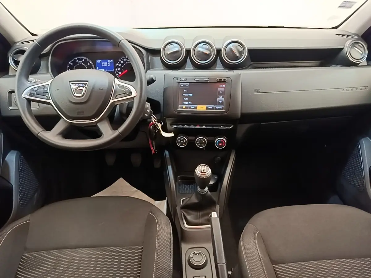 Vue intérieure avant du tableau de bord du Dacia Duster 2021, volant multifonctions et écran tactile central.