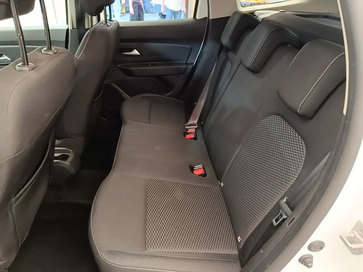 Vue latérale droite de la banquette arrière noire du Dacia Duster blanc, avec ceinture de sécurité visible.