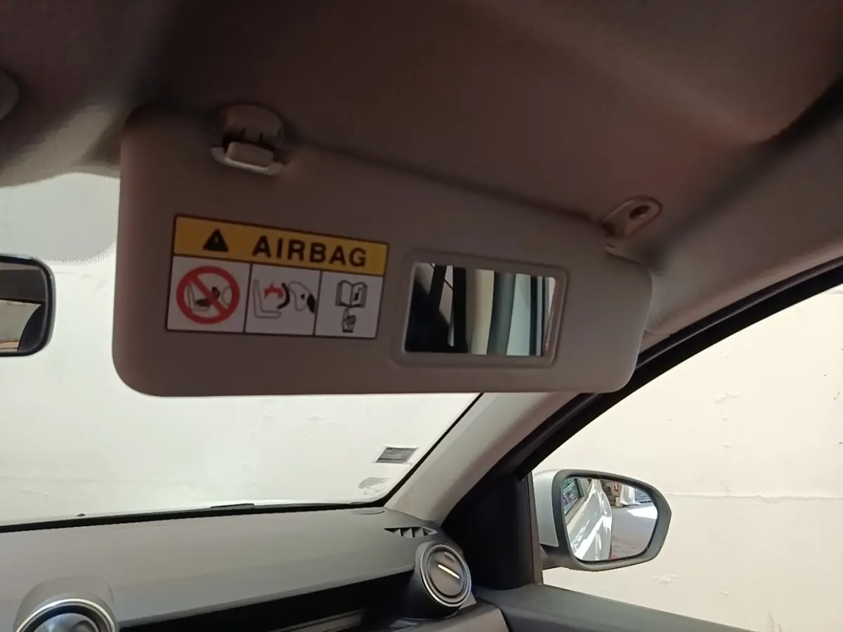 Vue intérieure côté conducteur du pare-soleil avec miroir et avertissement airbag du Dacia Duster blanc 2021.