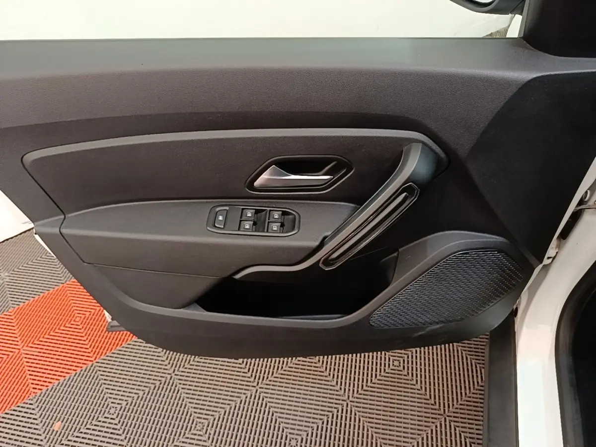 Vue intérieure de la porte avant gauche du Dacia Duster blanc, avec commandes électriques des vitres et poignée noire.