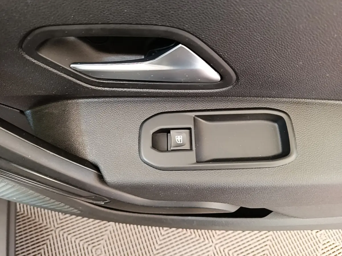 Détail de la poignée intérieure et commande de lève-vitre côté conducteur du Dacia Duster blanc 2021.
