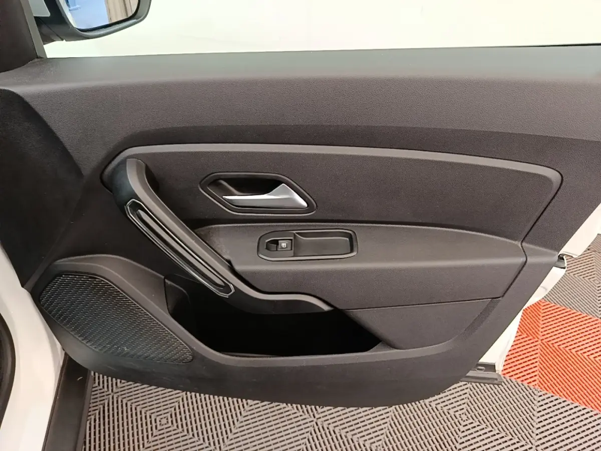 Vue intérieure de la porte avant gauche du Dacia Duster blanc, avec poignée argentée et commande de vitre électrique.