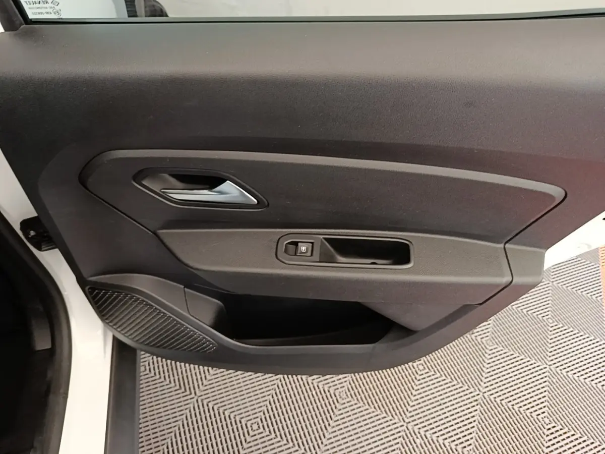 Vue rapprochée de la porte avant gauche blanche du Dacia Duster 2021, avec poignée intérieure et bouton de verrouillage.