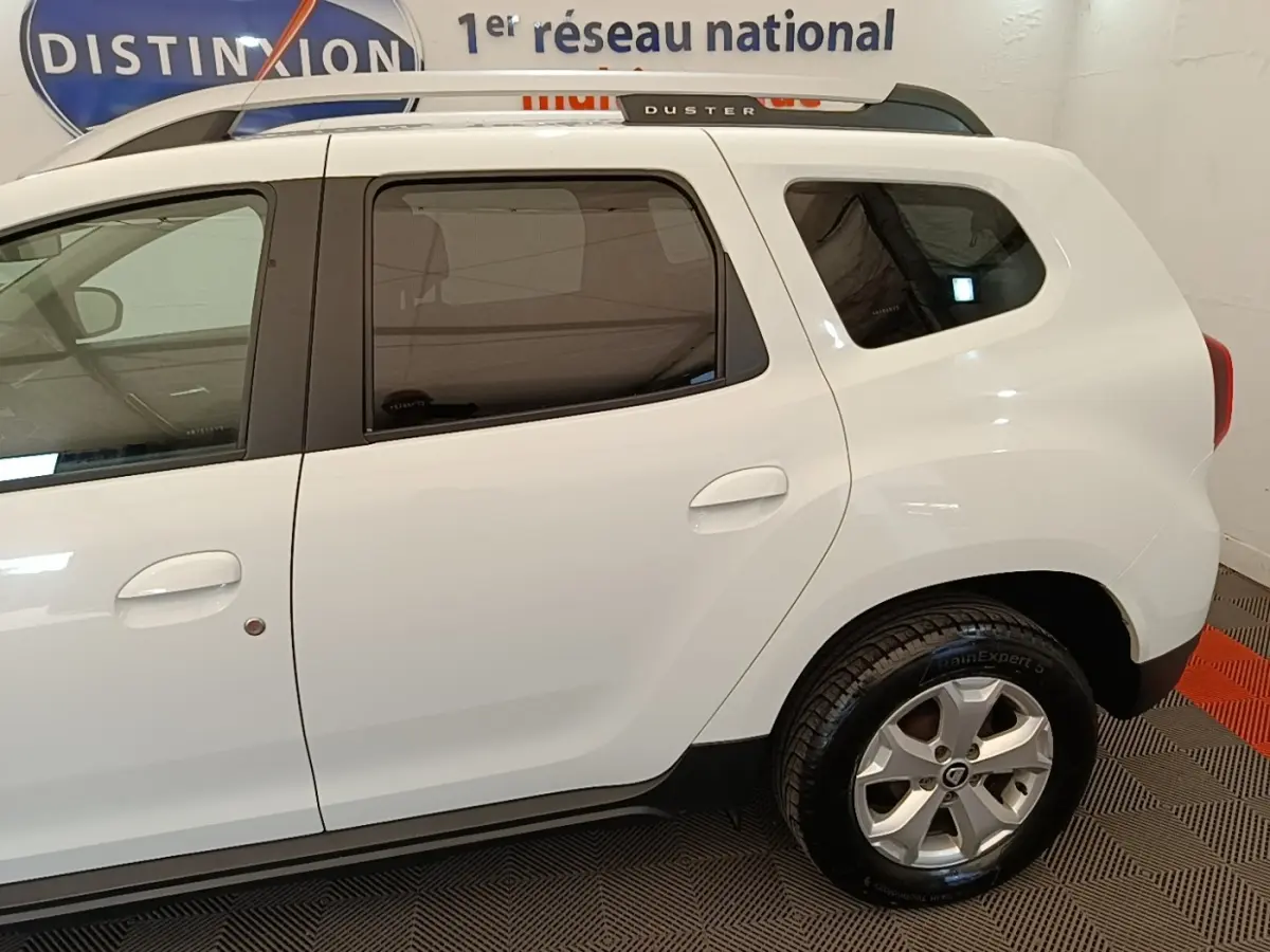 Vue latérale droite d'un Dacia Duster blanc 2021 avec vitres teintées et jantes alliage.