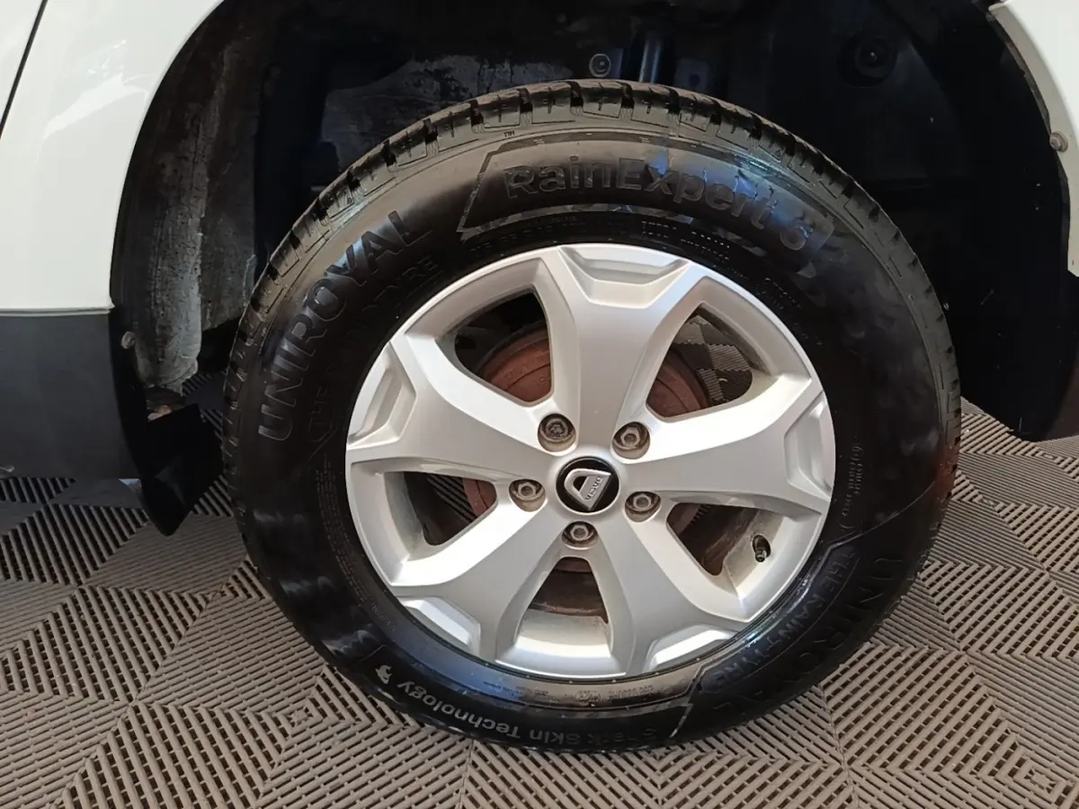 Gros plan sur la roue avant gauche blanche du Dacia Duster avec jante alliage et pneu UniRoyal.