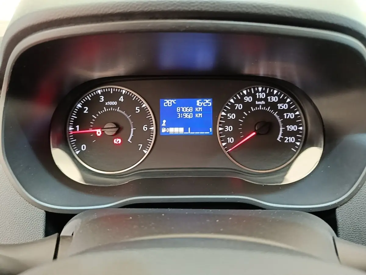 Vue rapprochée du tableau de bord du Dacia Duster blanc 2021, affichage digital et compte-tours analogiques.