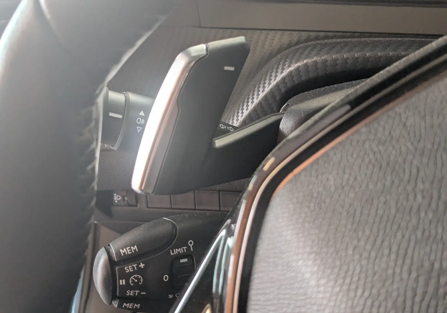 Gros plan sur le levier de commande multifonction et palettes au volant du Peugeot 2008 Hybrid 145 finition Allure.
