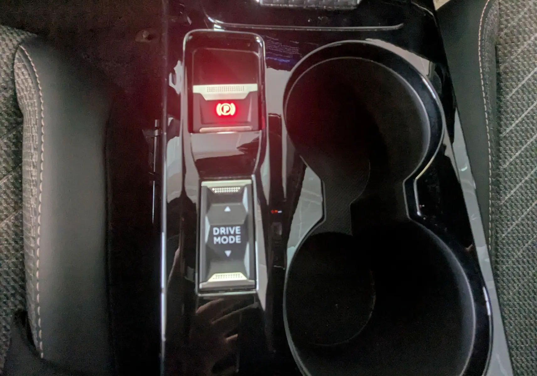 Vue rapprochée du levier de mode de conduite et frein à main électronique sur la console centrale noire du Peugeot 2008 Hybrid 145.