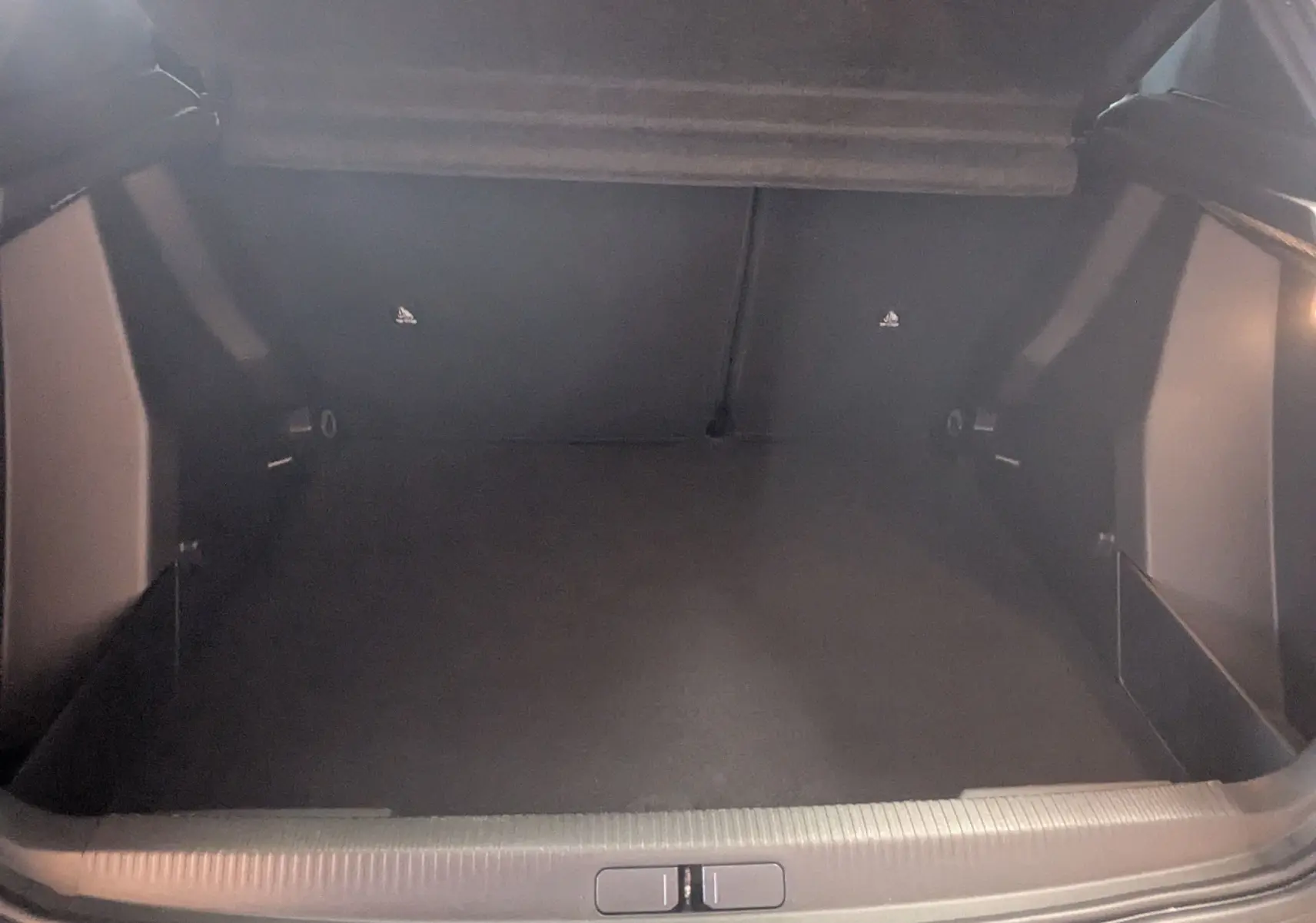Vue intérieure du coffre spacieux et vide du Peugeot 2008 Hybrid 145 e-DCS6 Allure, avec revêtement noir.