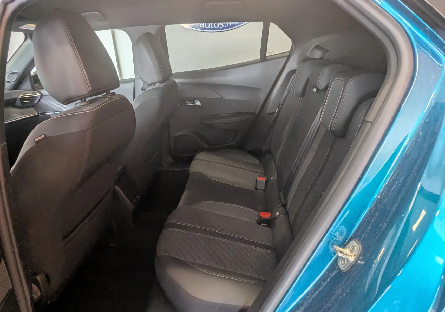 Vue intérieure côté gauche des sièges arrière en tissu gris noir d'un Peugeot 2008 Hybrid 145 Bleu Obsession avec portière ouverte.
