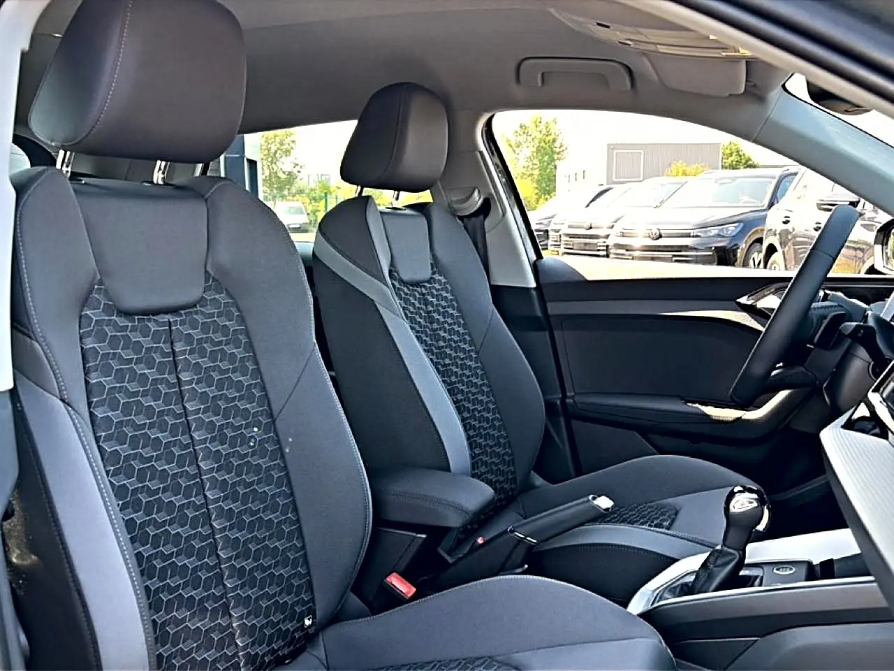Vue intérieure côté droit de l'Audi A1 Sportback 2026 avec sièges sport noirs à motif hexagonal et accoudoir central.