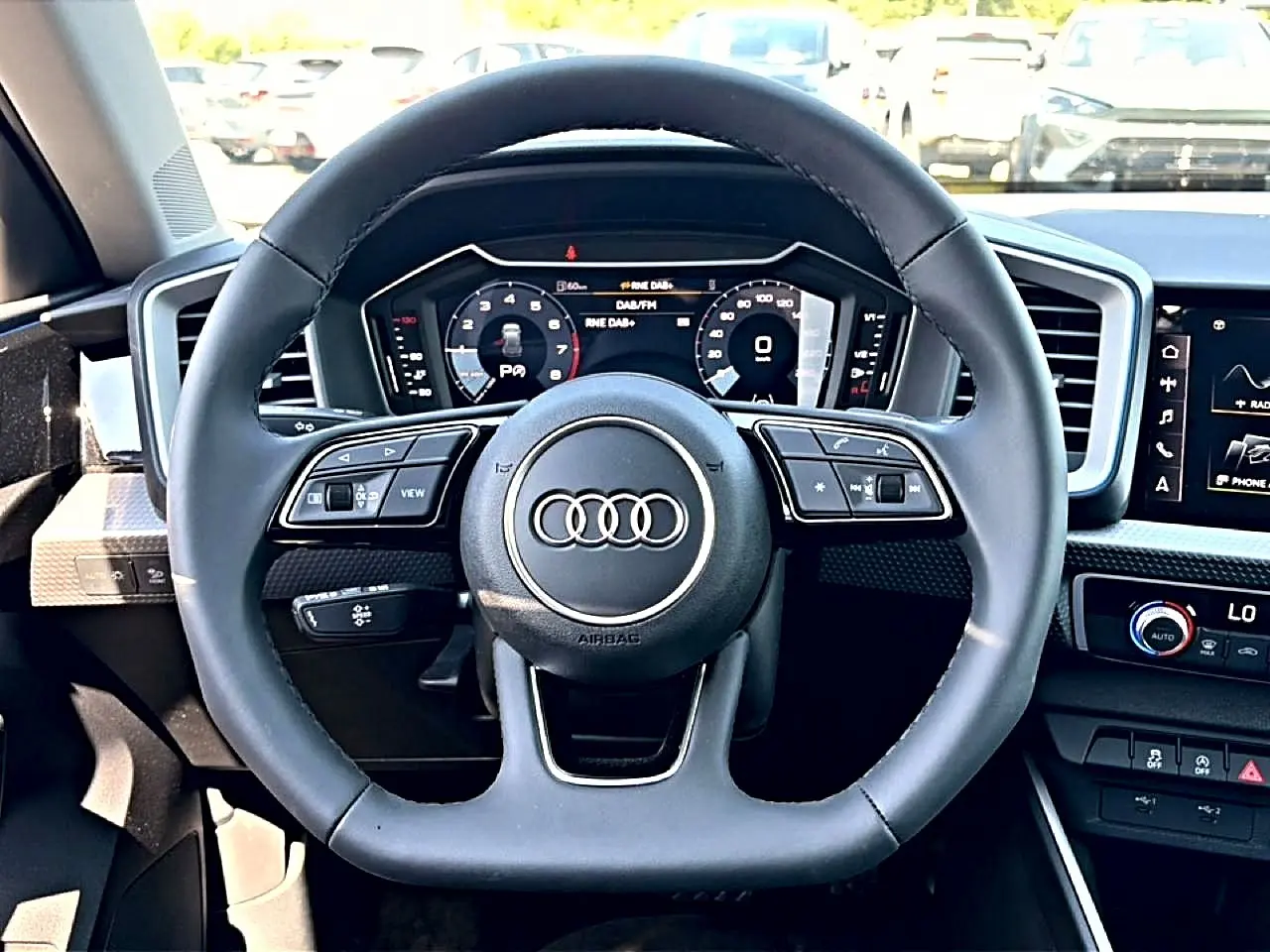 Vue frontale du volant cuir multifonction noir et du tableau de bord numérique de l'Audi A1 Sportback blanc/noir.