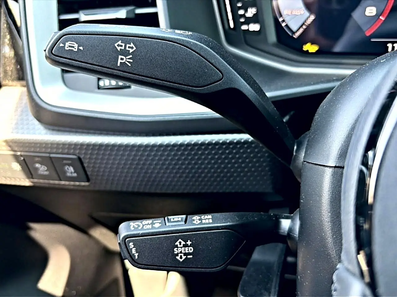 Gros plan sur les commandes au volant d'une Audi A1 Sportback 2026, avec leviers noirs et tableau de bord numérique.