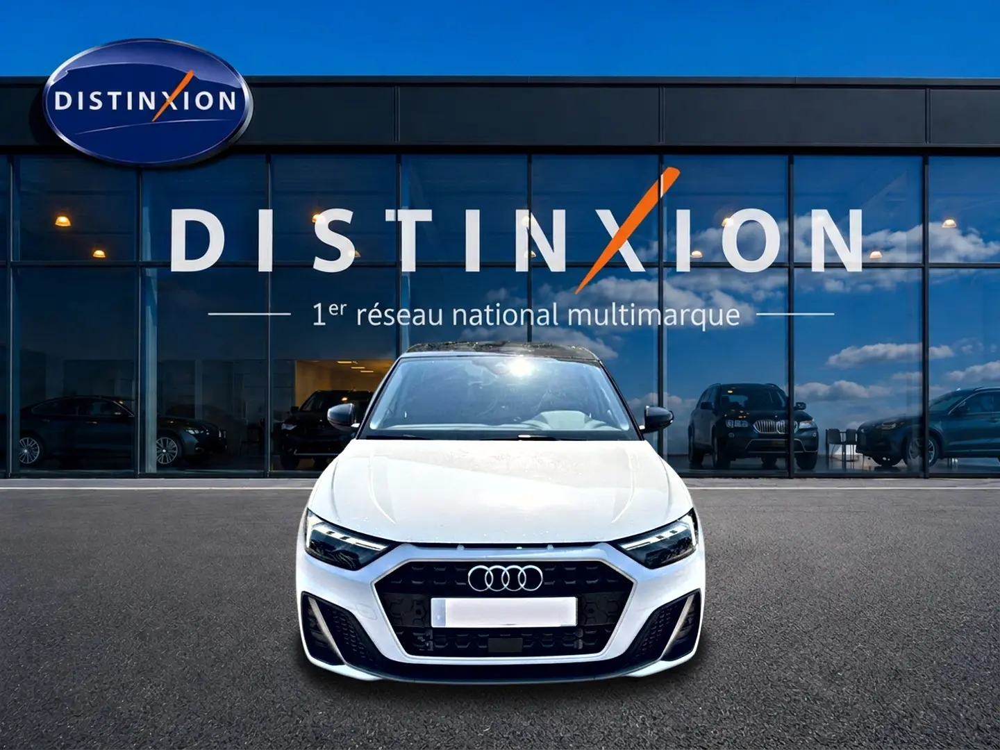 Audi A1 Sportback blanc et noir vue de face, avec calandre noire et logo Audi devant un showroom Distinxion.