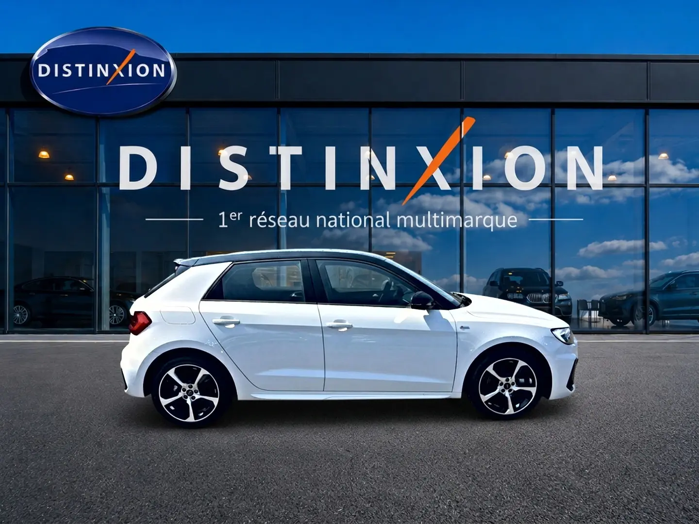 Audi A1 Sportback blanc toit noir en profil droit devant une vitrine Distinxion, avec jantes alliage noires et blanches.