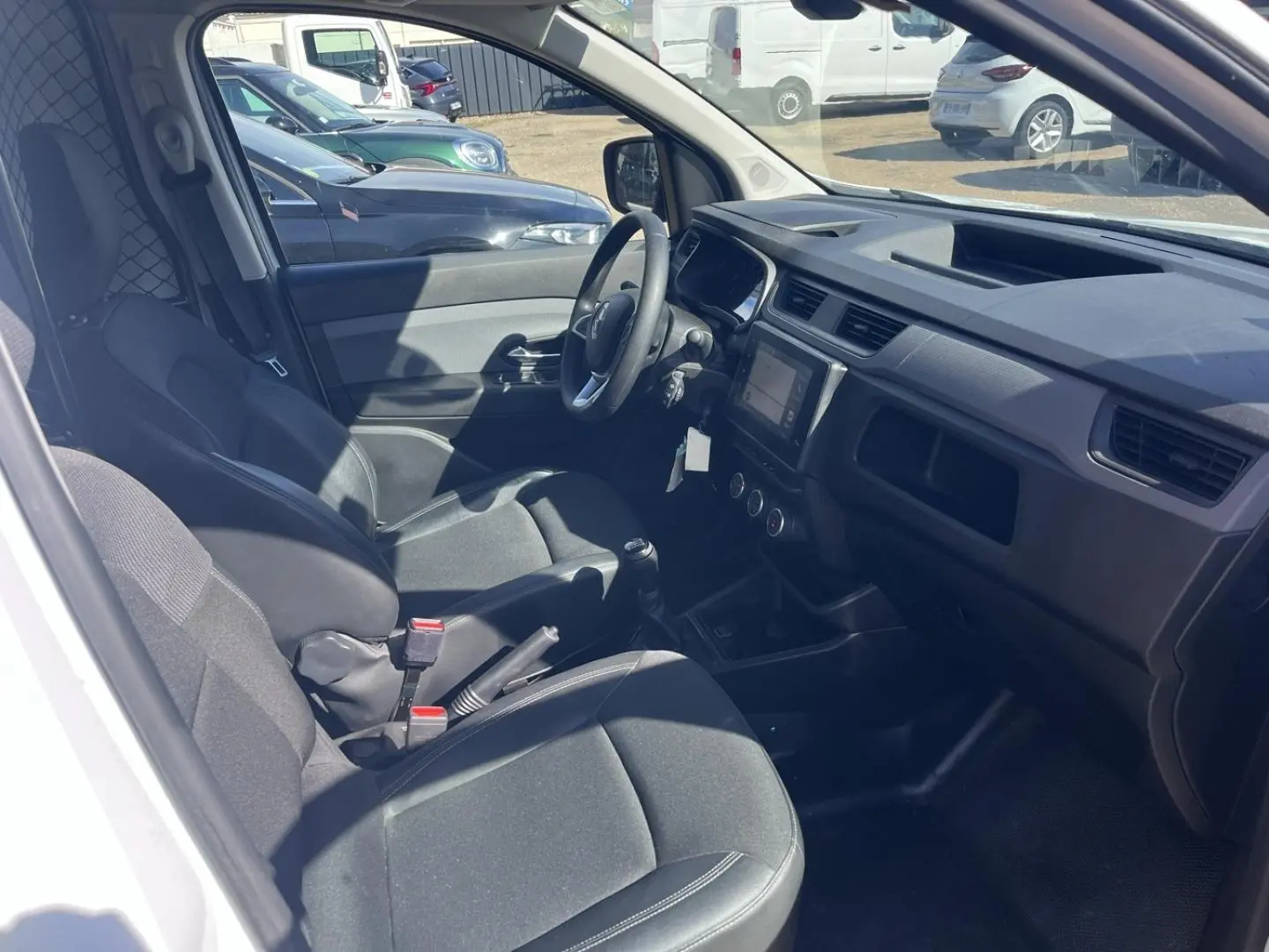 Vue intérieure côté conducteur du Renault Express Van blanc glacier 2022, montrant sièges en tissu noir et tableau de bord avec écran tactile.