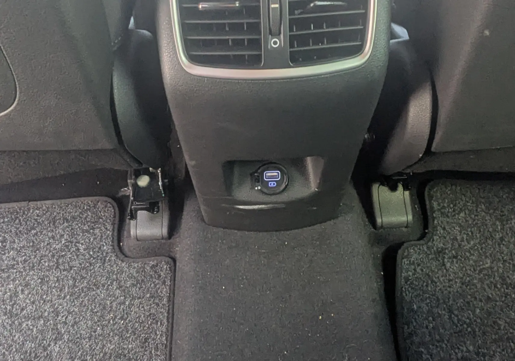 Vue rapprochée de la console centrale arrière noire du Hyundai Tucson 2019 avec bouches d’aération et prise USB.