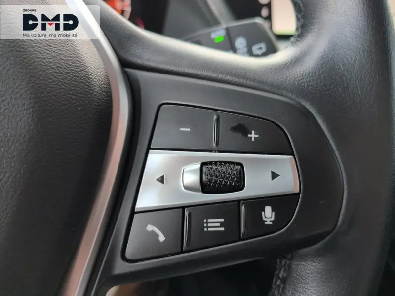 Gros plan sur les commandes multifonctions du volant cuir noir de la BMW Série 1 118iA 2024 en Saphirschwarz métallisé.