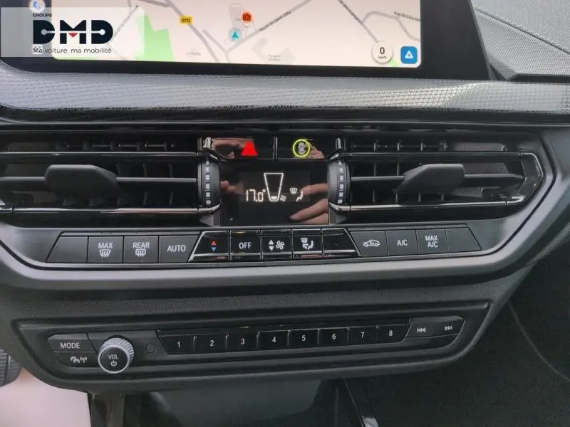 Vue rapprochée du tableau de bord de la BMW Série 1 118iA 2024, avec commandes climatisation et écran tactile noir.