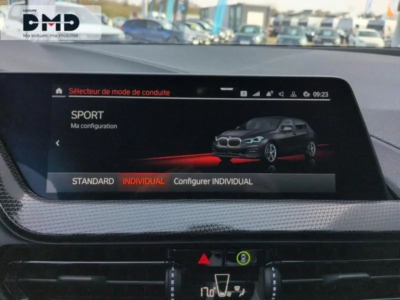 Écran tactile intérieur montrant la BMW Série 1 118iA Saphirschwarz en mode conduite Sport, vue 3/4 avant.