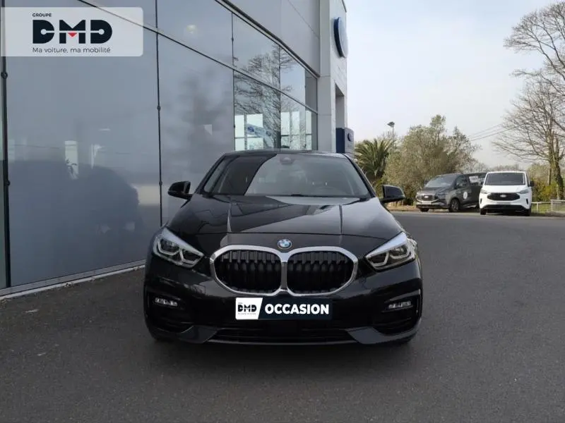 BMW Série 1 118iA 2024 en Saphirschwarz métallisé vue de face, calandre et phares LED bien visibles.