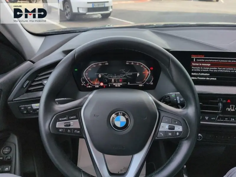Vue intérieure centrée sur le volant cuir multifonction d'une BMW Série 1 118iA 2024, avec tableau de bord numérique allumé.