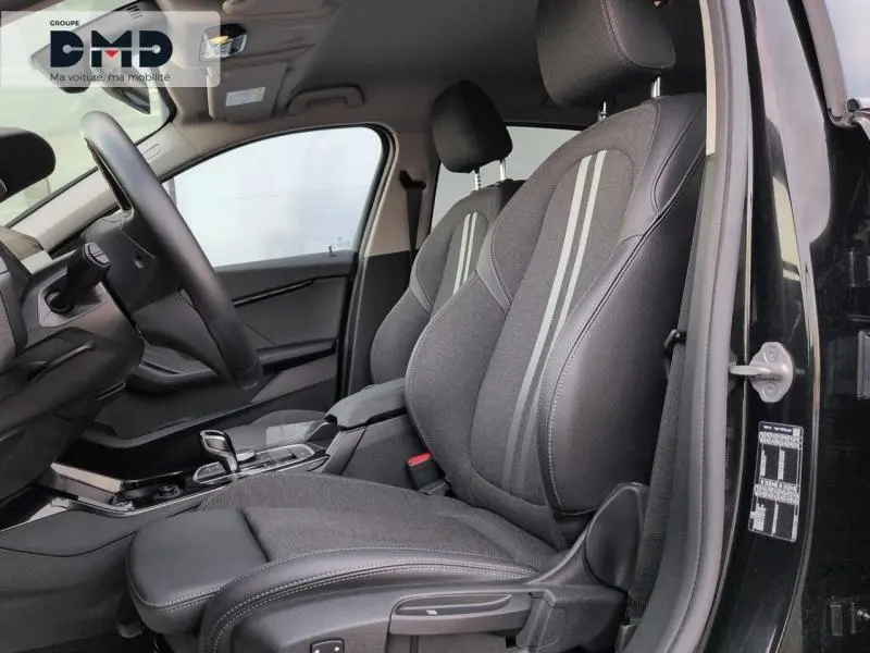 Vue intérieure côté conducteur de la BMW Série 1 118iA 2024 avec sièges sport tissu/similicuir anthracite et bandes grises.