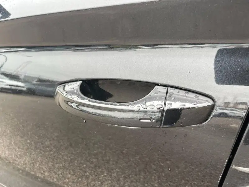 Poignée de porte chromée avec gouttes d'eau sur portière noire Magic Nacré d'un Skoda Kodiaq vue latérale rapprochée.