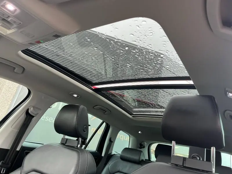 Vue intérieure du toit panoramique en verre avec pluie visible, sièges cuir noir du Skoda Kodiaq 2018.