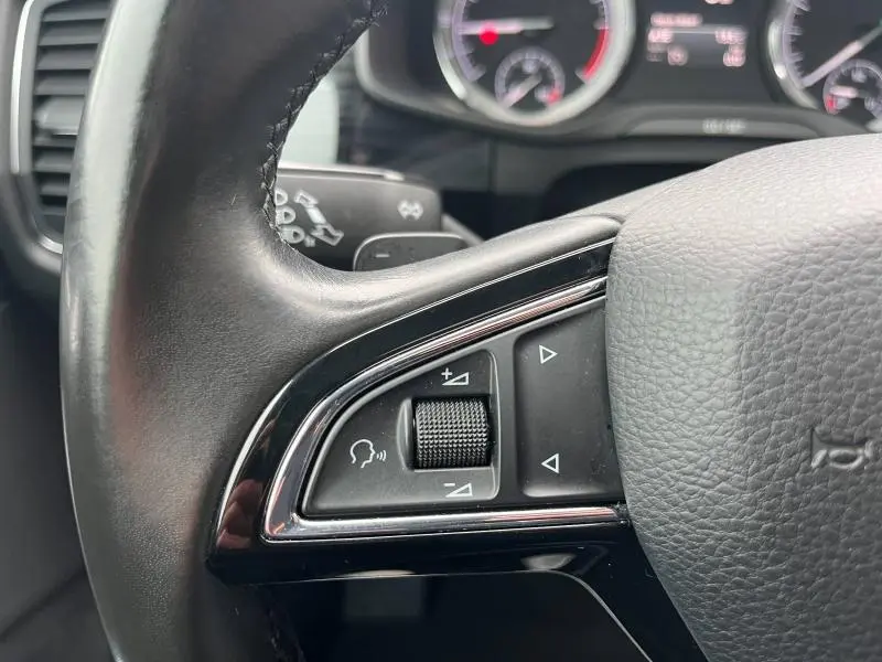 Gros plan sur les commandes gauche du volant cuir noir du Skoda Kodiaq 2.0 TDI 190 Style, avec molette et boutons triangulaires.