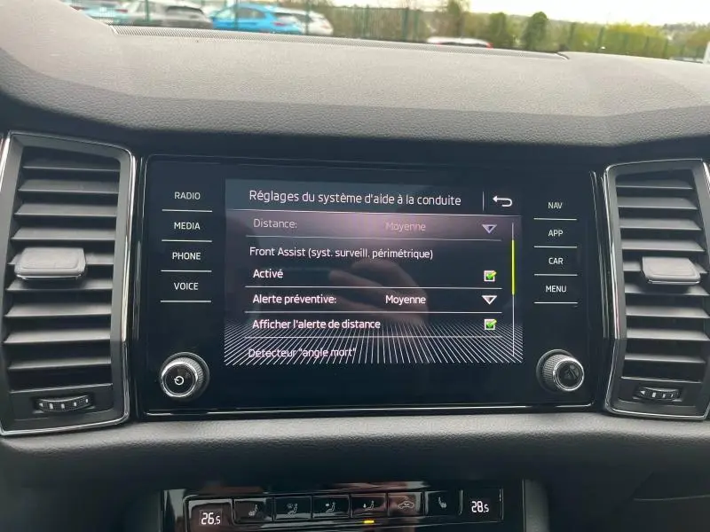 Vue rapprochée de l’écran tactile central du Skoda Kodiaq noir Magic Nacré, affichant les réglages d’aide à la conduite.