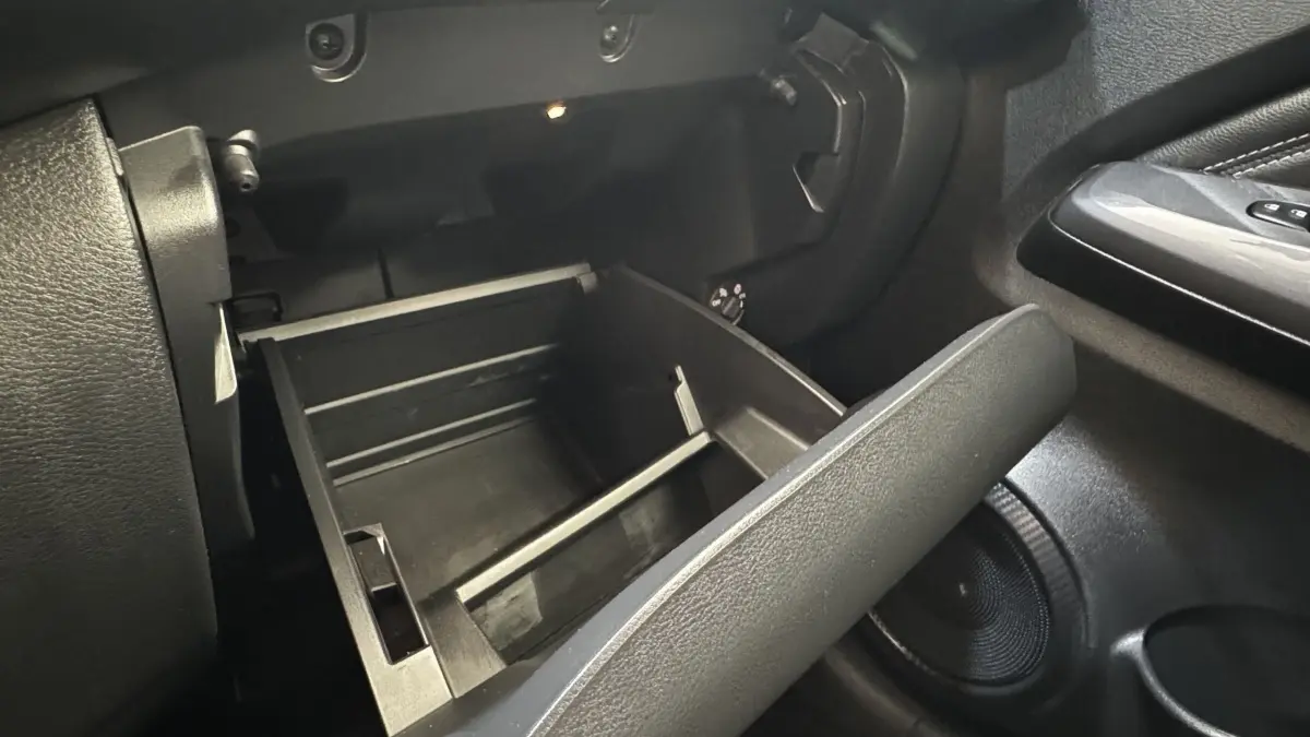 Intérieur du Nissan Juke Hybrid 143 Business+ 2023, vue sur la boîte à gants ouverte côté passager en plastique noir.