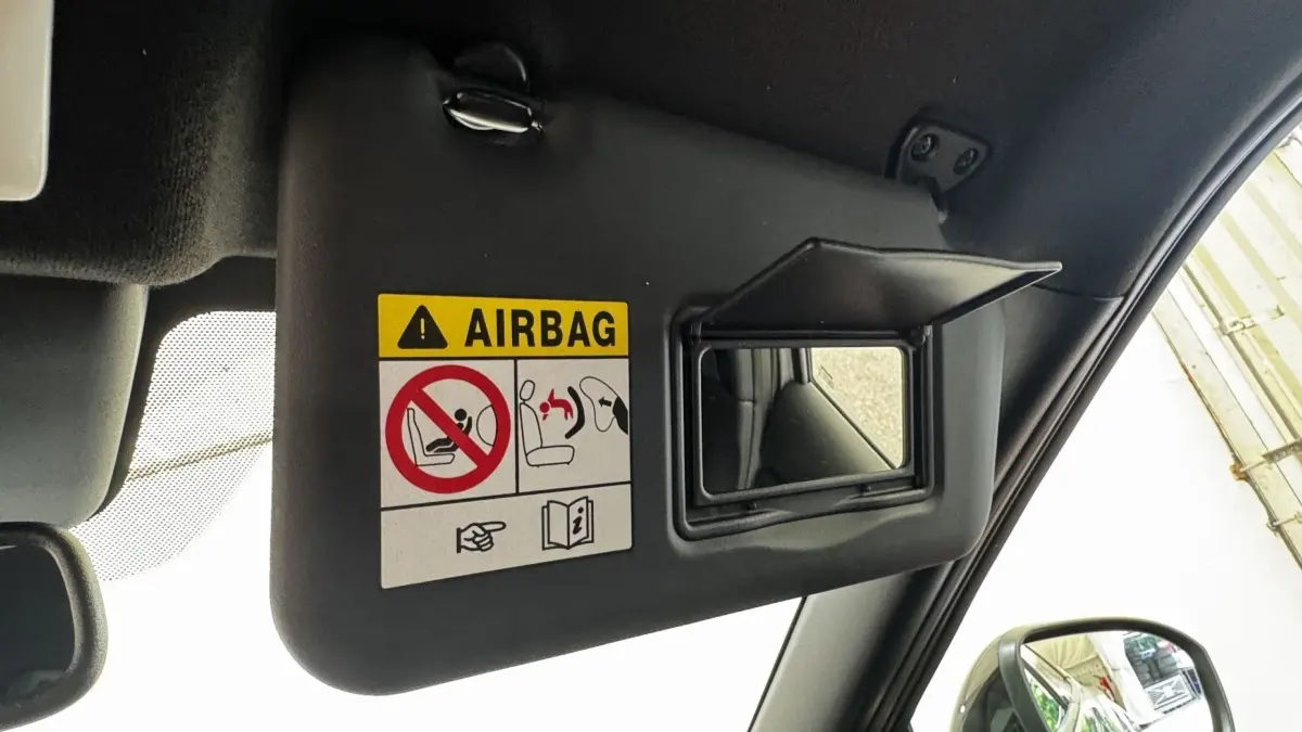 Détail du pare-soleil côté conducteur avec miroir et avertissement airbag dans un Nissan Juke gris foncé 2023.