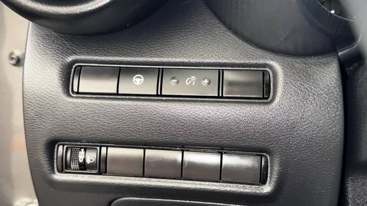 Gros plan sur les commandes noires du tableau de bord du Nissan Juke Hybrid 143 Business+ gris foncé, 2023.