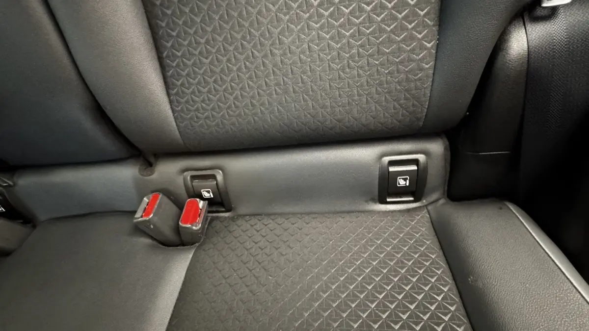 Gros plan sur la banquette arrière noire du Nissan Juke Hybrid 143 Business+ avec fixation Isofix et boucles de ceinture rouges.